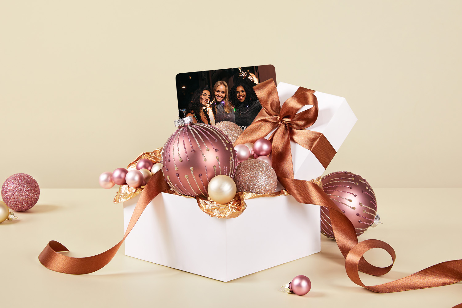 Gaveeske med julekuler og andre julepynt med et personlig gavekort på toppen