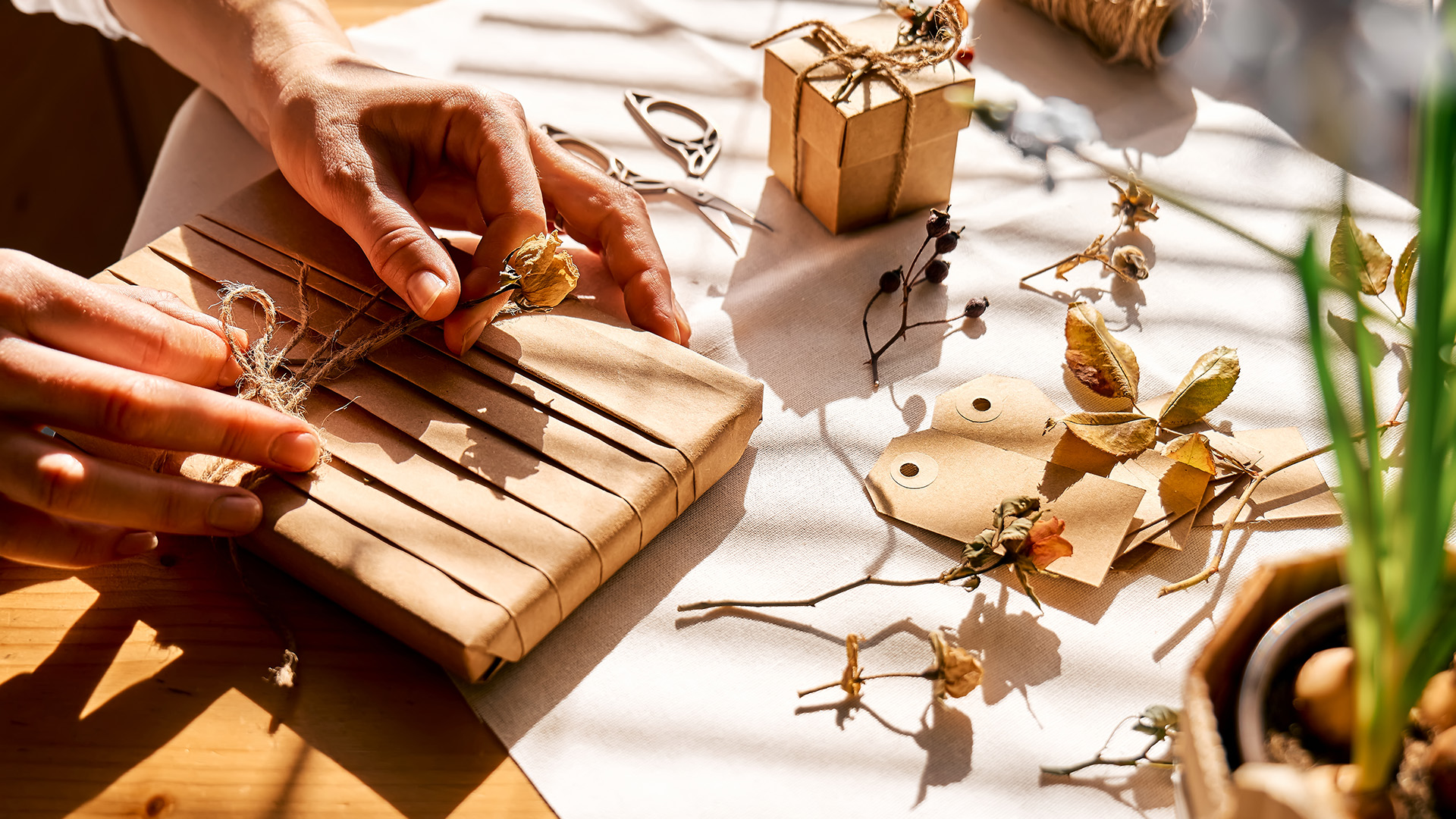 Kvinne dekorerer innpakkede gaver med resirkulert papir med tørkede blomster