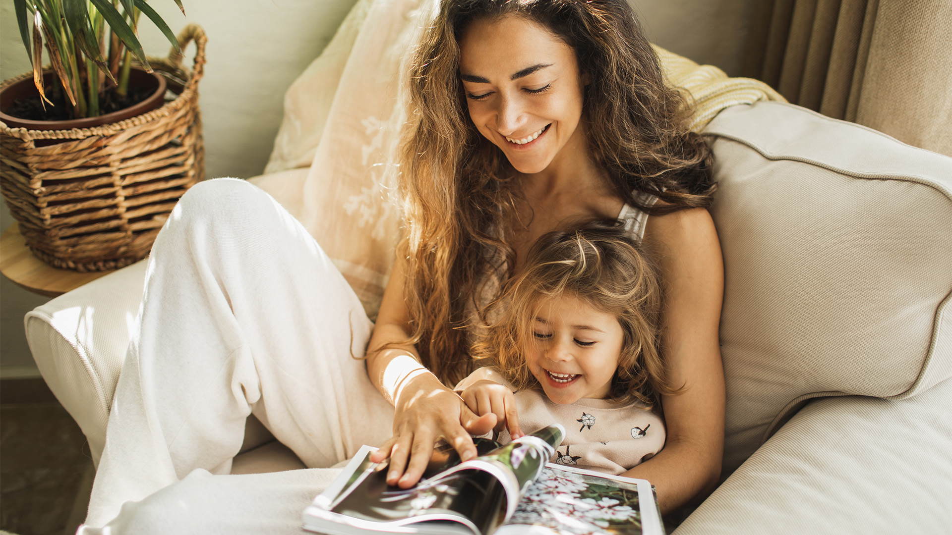 Dame og et barn som sitter i lenestol og ser på en fotobok