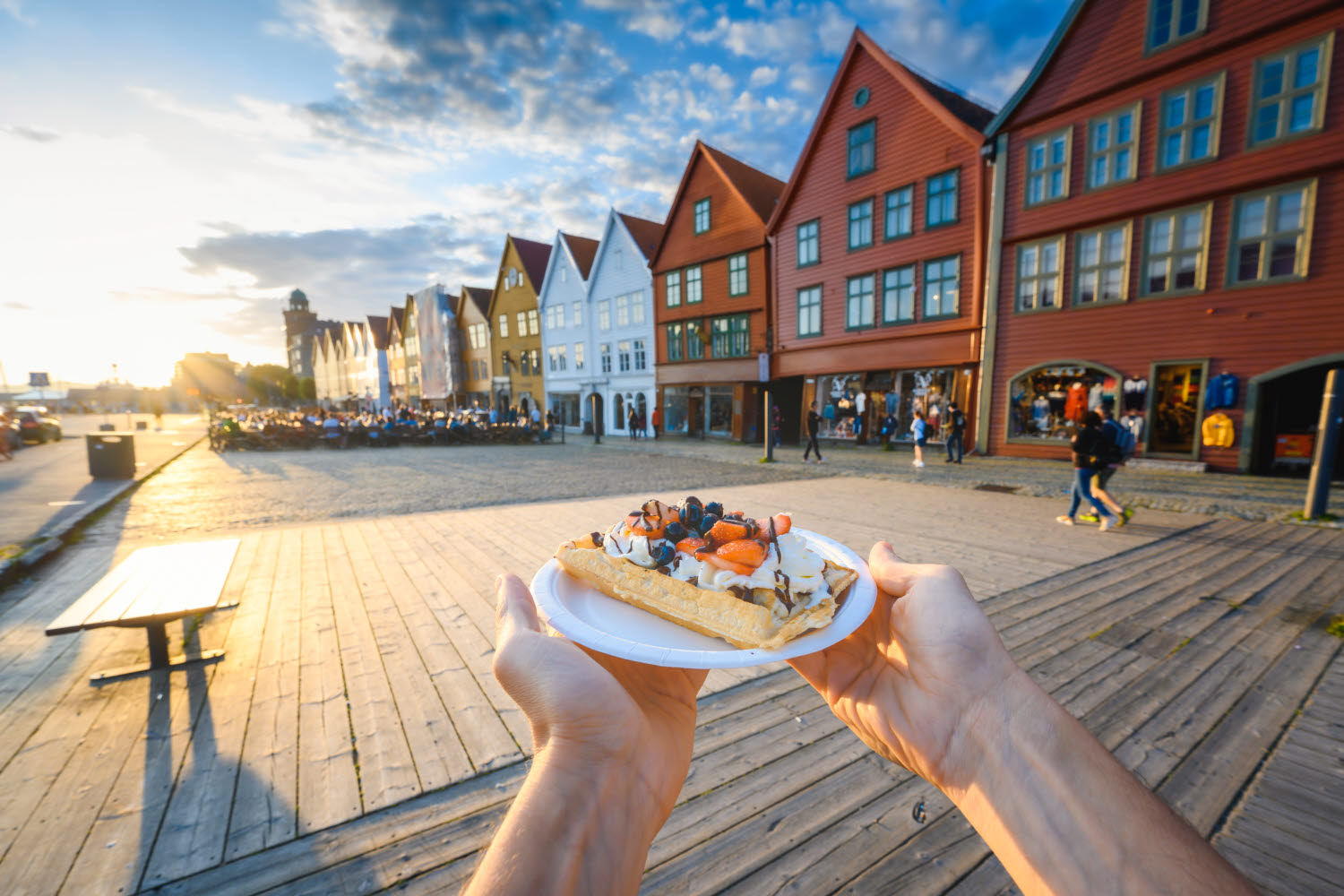 Person som holder en tallerken med belgisk vafler på bryggen i Bergen
