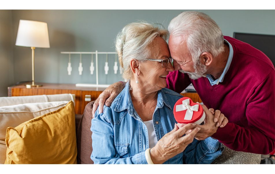 Et eldre par som holder en hjerteformet gaveeske